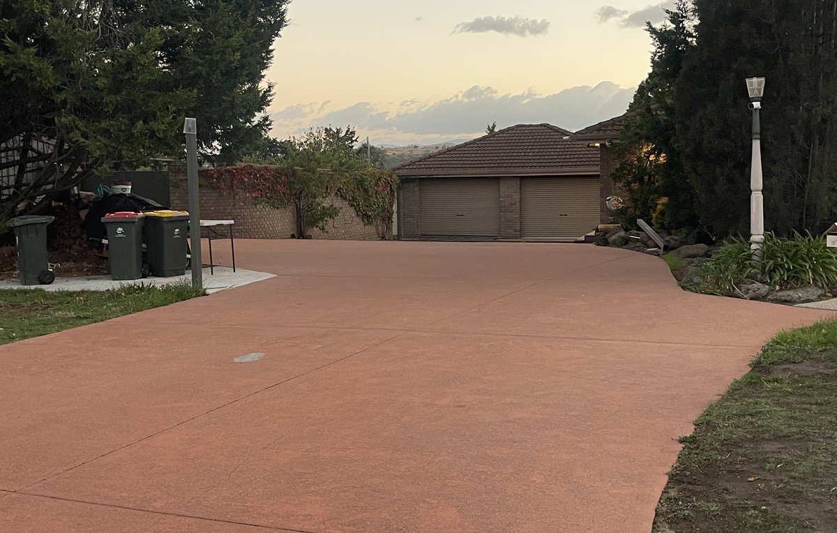 Red concrete driveway after professional cleaning by Refined Grounds