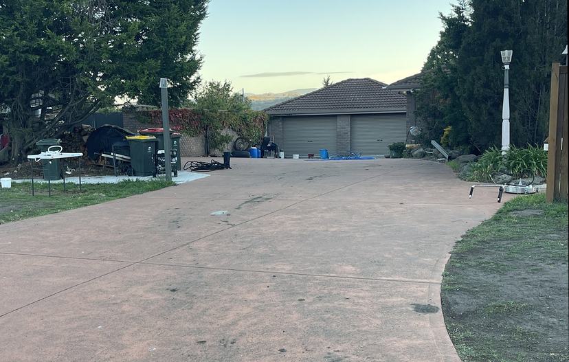 Faded, dirty coloured concrete driveway before pressure cleaning