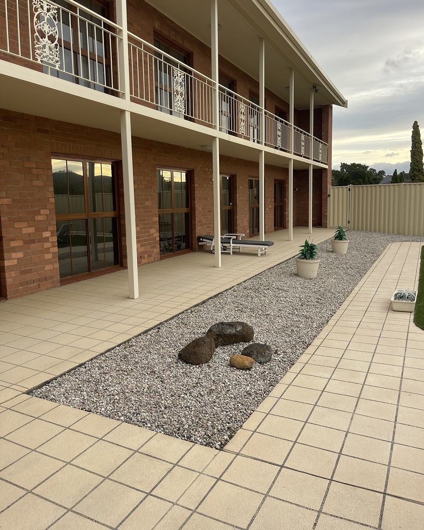 Clean tiled walkway and gravel garden beside a two-storey commercial building