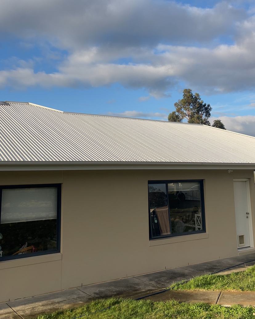 Clean cream Colorbond roof on a rendered home under a blue sky
