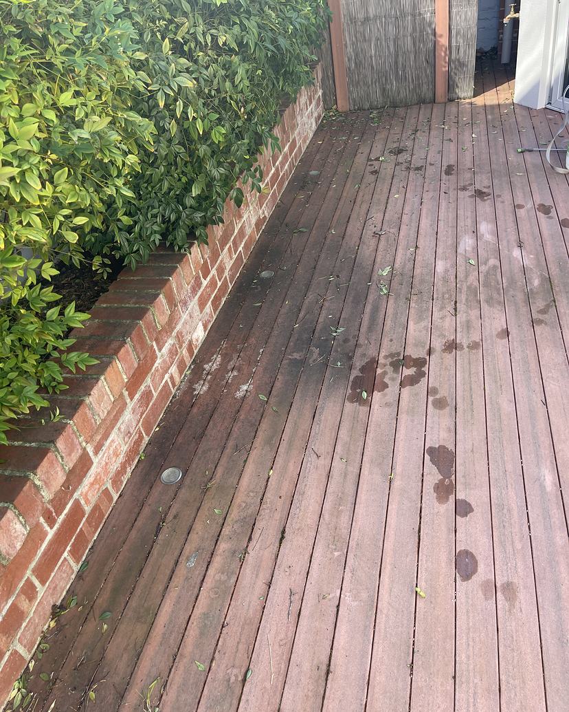 Dirty timber deck beside a brick planter before cleaning