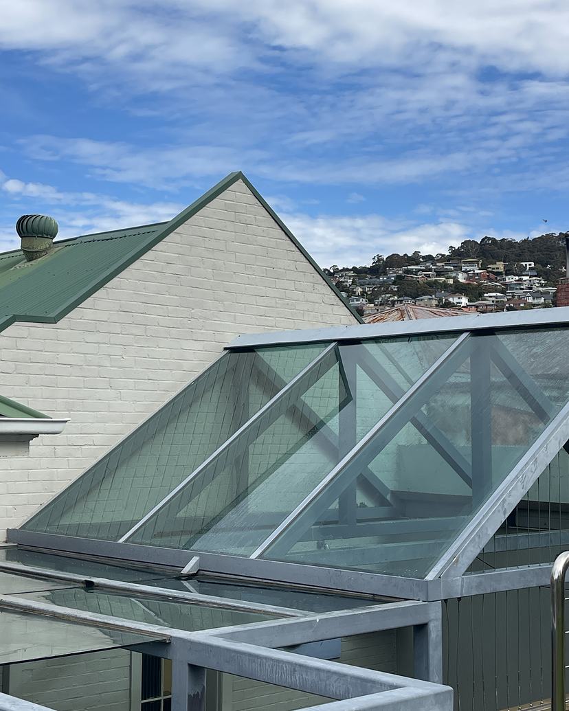 Clean glass skylight roof in Sandy Bay with the hillside of homes behind