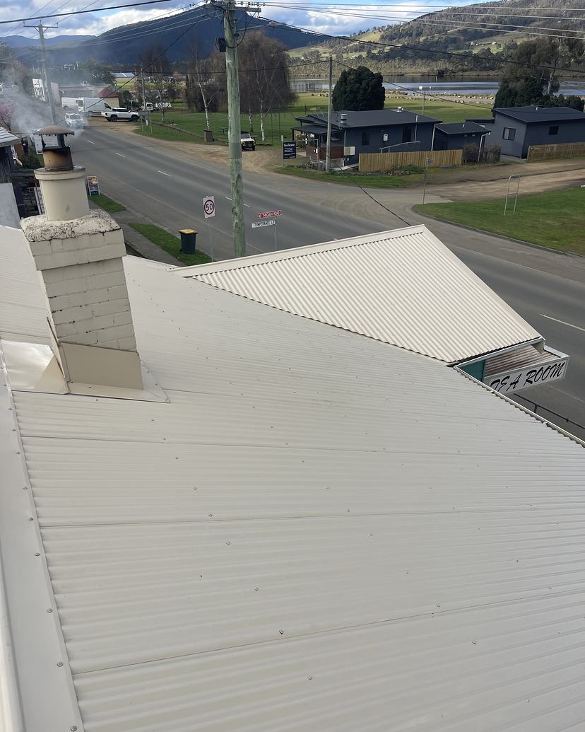 Clean cream Colorbond roof with a brick chimney in Franklin after roof cleaning