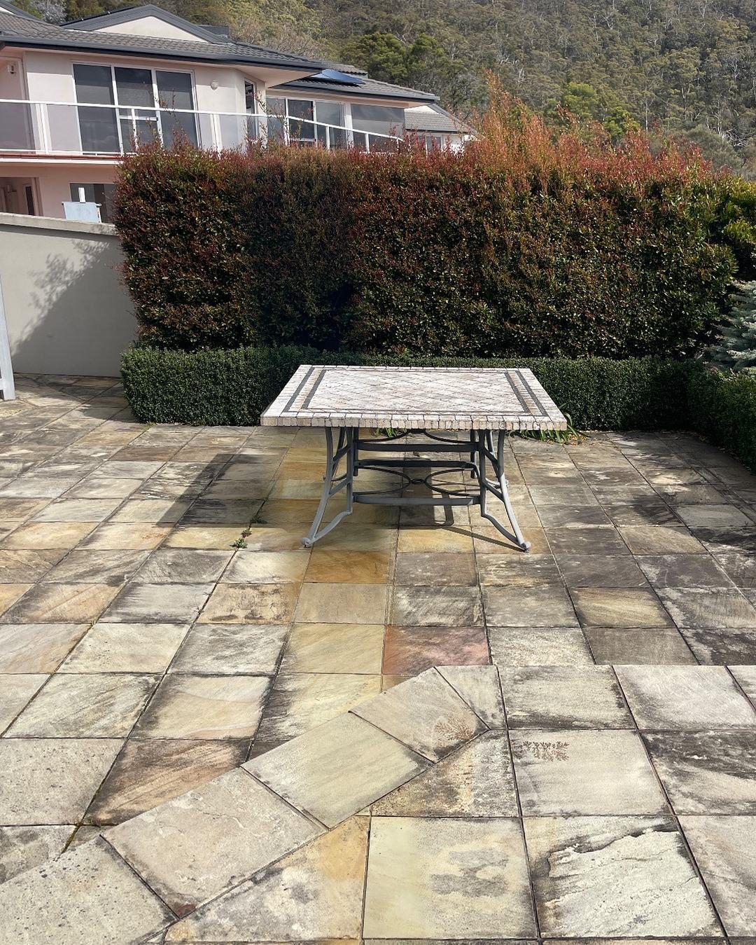 Sandstone courtyard in Sandy Bay with one clean stripe through the grime, showing the golden stone under it