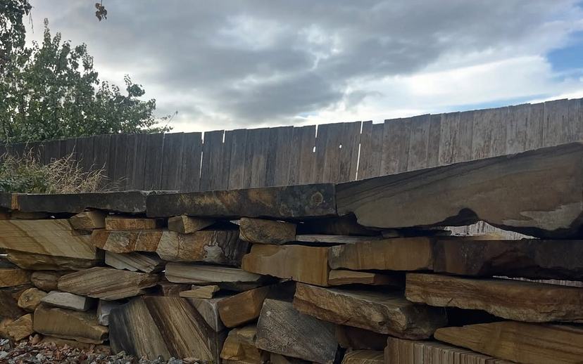 Stacked sandstone retaining wall darkened with grime before cleaning