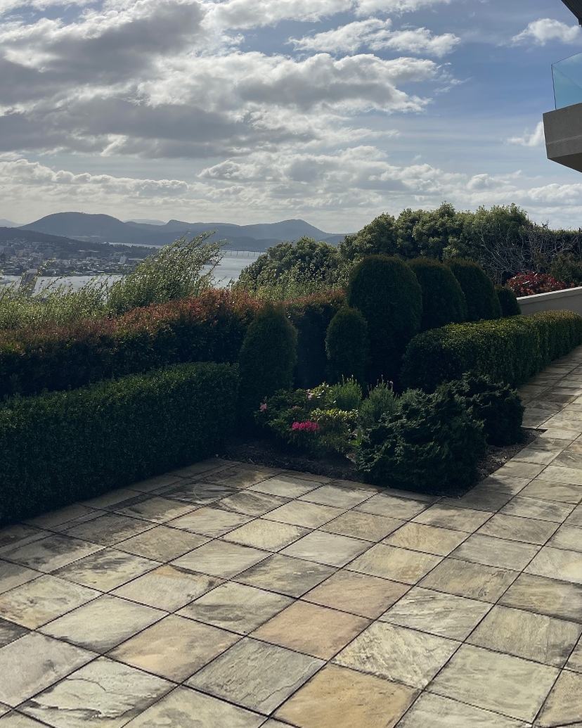 Sandstone terrace in Sandy Bay with dark staining and moss, before cleaning