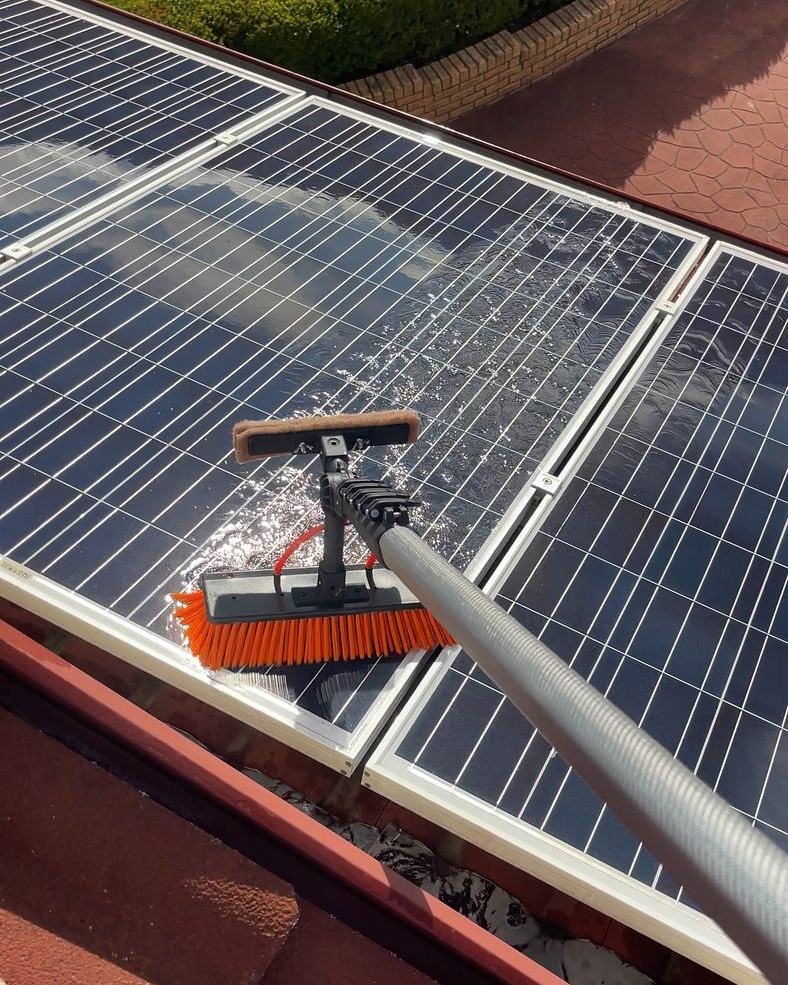 Soft brush on a pole cleaning solar panels with purified water on a Hobart roof