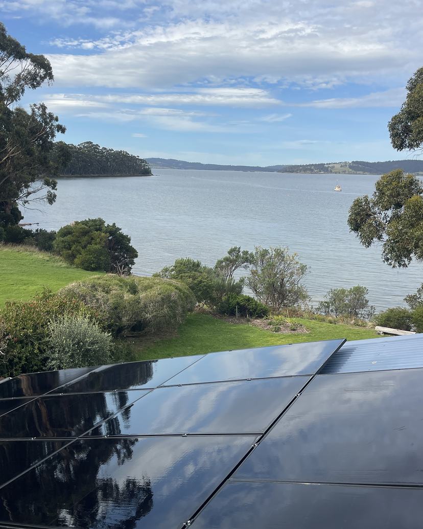 Freshly cleaned black solar panels in Woodbridge looking out over the water and a moored yacht